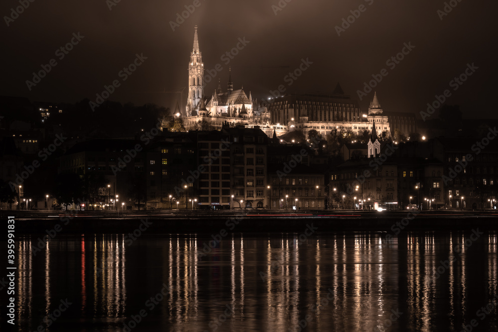 Fototapeta premium Floodlit Fisherman's Bastion of Budapest during a cold night of November in Hungary, with the river Danube in the foreground