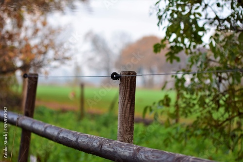 Close-up of a pasture fence made of wooden slats and blue wire