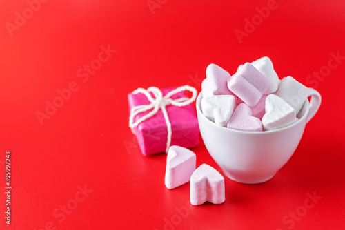 Red background with cocoa cup with marshmallow and gift for Valentine's day