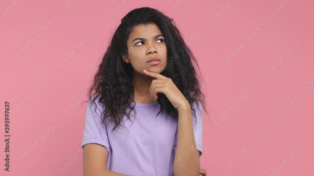 Excited pensive young african american woman 20s years old in casual violet t-shirt posing isolated on pink background in studio. People lifestyle concept. Holding index finger up with great new idea Excited pensive young african american woman 20s years old in casual violet t-shirt posing isolated on pink background in studio. People lifestyle concept. Holding index finger up with great new idea