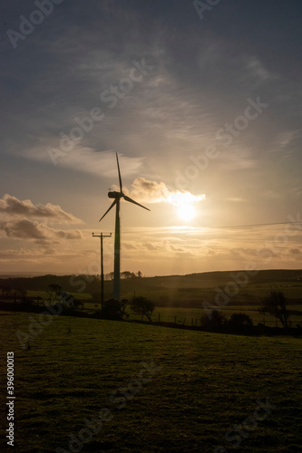 a wind turbine spinning in the sunset providing clean green energy