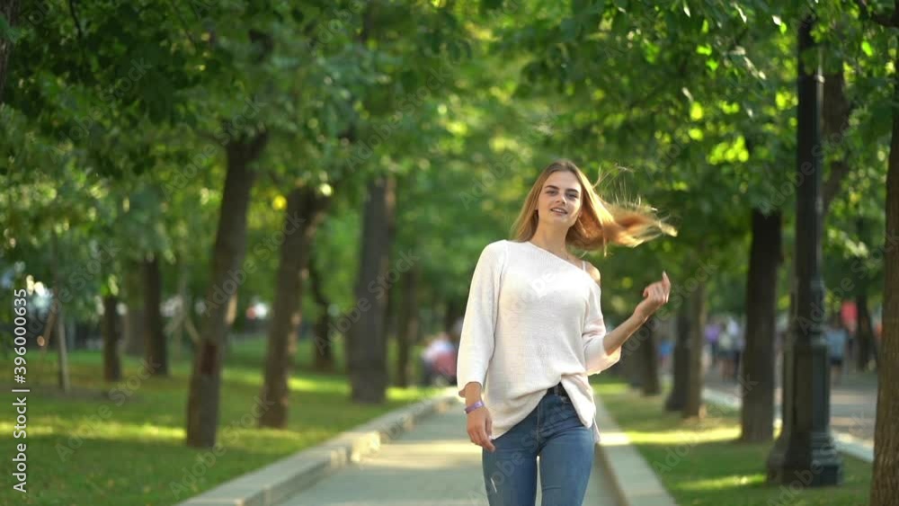 Beautiful girl walking down the street with a smile. Slow motion Beautiful girl walking down the street with a smile. Slow motion