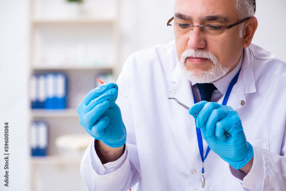 Old male expert criminologist working in the lab for evidence Old male expert criminologist working in the lab for evidence