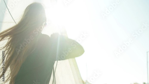 A young athlete learns to set sail on a yacht during a training race on sailing vessels. Bright glare of the sun in the camera.