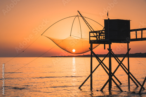 Paysage de Loire atlantique: une pêcherie de bord de mer avec le soleil couchant et le soleil est pris dans les filets de pêche © jef 77