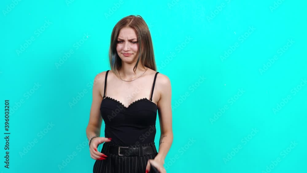 Sad teenager looks to the left and does not recommend profuse. Charming girl, dressed in black T-shirt with cleavage, in the studio on a blue background. female casting for TV commercial, student Sad teenager looks to the left and does not recommend profuse. Charming girl, dressed in black T-shirt with cleavage, in the studio on a blue background. female casting for TV commercial, student
