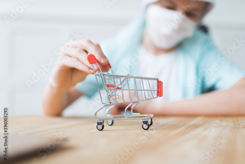 A boy wearing a disposable face mask is playing with a mini cart