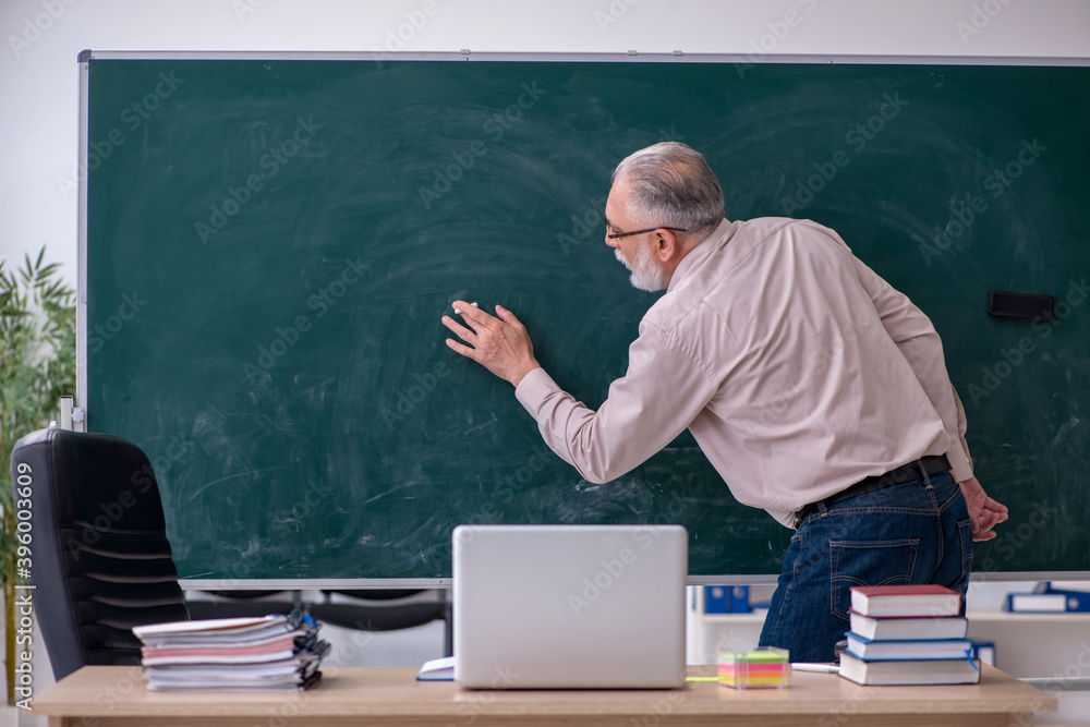 Old male teacher sitting in the classroom