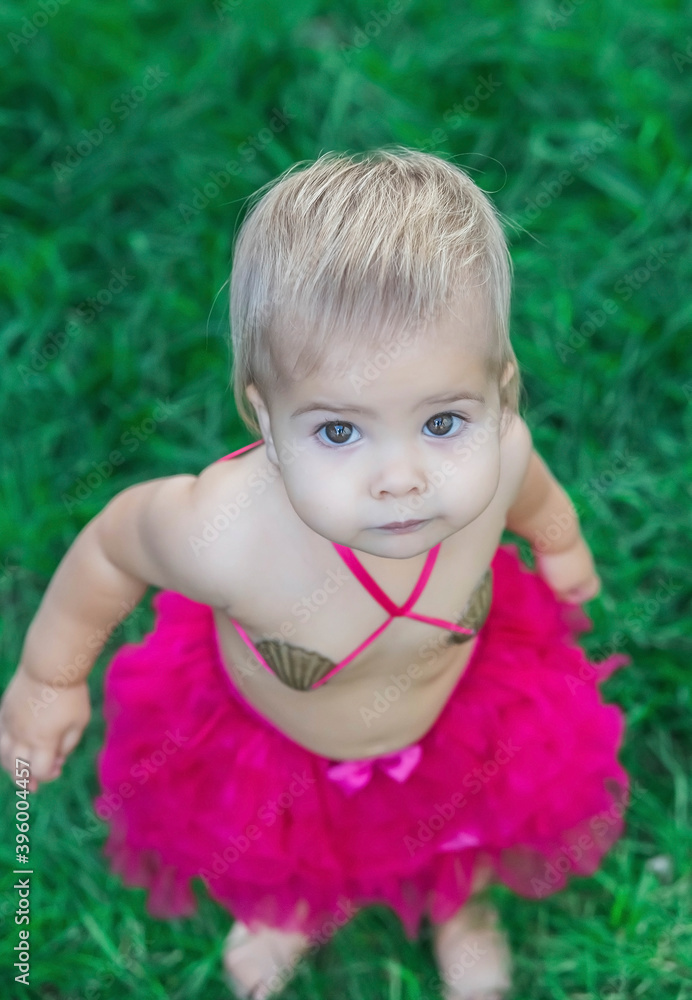 baby in a swimsuit made of seashells sunbathes on the lawn baby in a swimsuit made of seashells sunbathes on the lawn