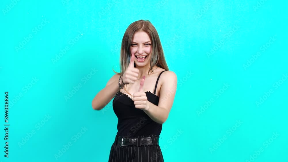 A successful teenager receives good news and is happy to say yes. Charming girl, dressed in black T-shirt with cleavage, in the studio on a blue background. female casting for TV commercial, student A successful teenager receives good news and is happy to say yes. Charming girl, dressed in black T-shirt with cleavage, in the studio on a blue background. female casting for TV commercial, student