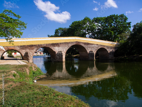 Ancient stone bridge crossing a river, reflection of the bridge in the green river, medieval rural town photo