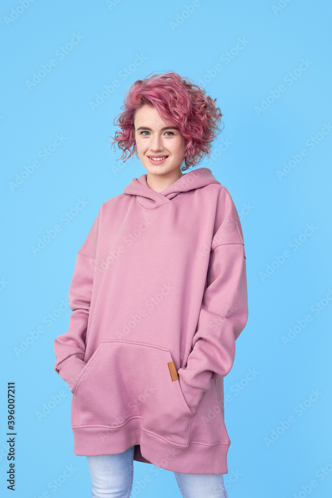 Girl with pink hair in stylish oversized casual hoodie standing and looking at camera