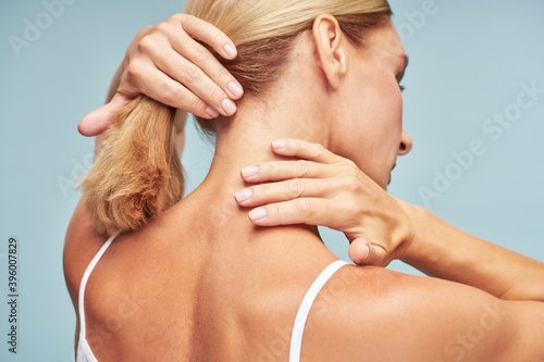 Konstfotografi Rear view of a mature woman touching her neck with soft and clean skin while sta