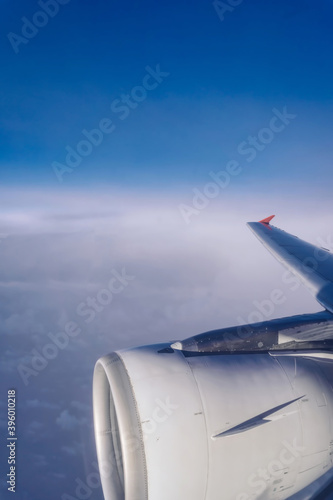The passenger plane transports passengers in the air, looking out from the glass window of the plane while traveling, and the wing flies in the beautiful clouds of the sky.
