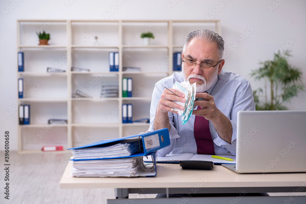 Old male accountant in budget planning concept in the office Old male accountant in budget planning concept in the office