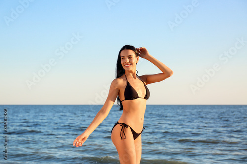 Beautiful young woman in black stylish bikini on beach