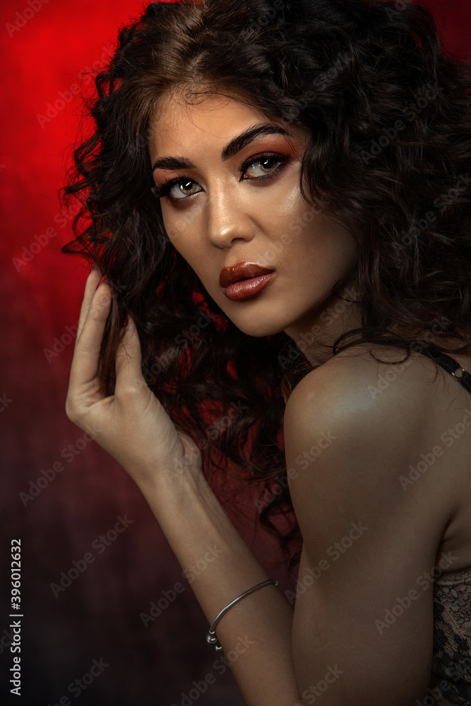 close up portrait of a brunette with a make up Afro curls low key on a red background close up portrait of a brunette with a make up Afro curls low key on a red background
