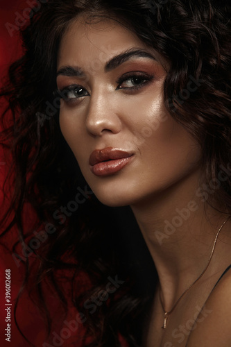 close up portrait of a brunette with a make up Afro curls low key on a red background