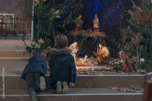 Bild auf Leinwand Children look at christmas creche with Joseph Mary and small Jesus in a crib