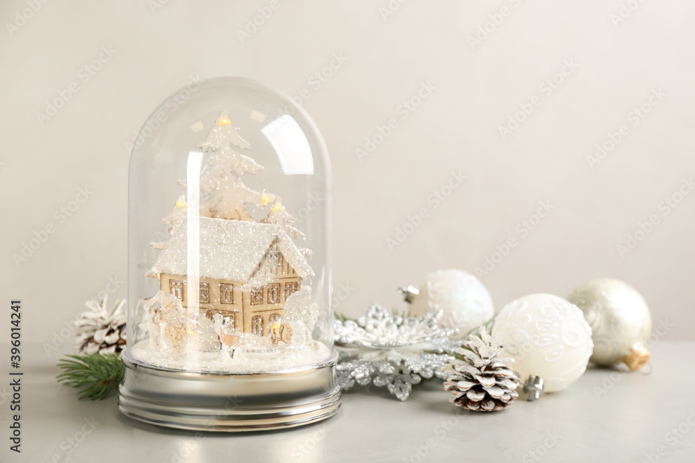 Beautiful snow globe and Christmas decor on light grey stone table. Space for text