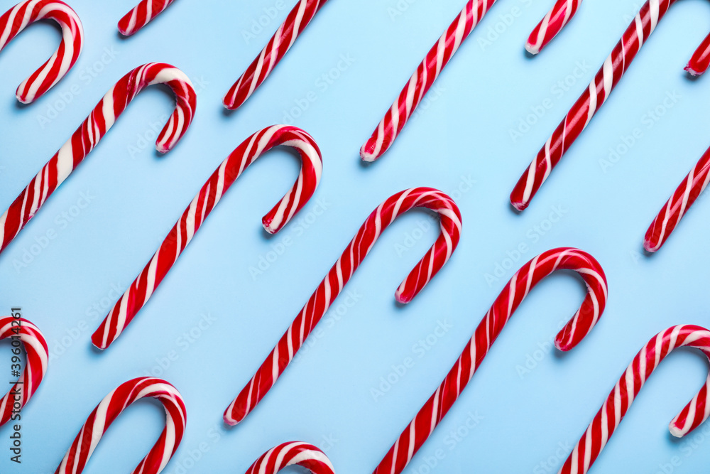 Sweet Christmas candy canes on light blue background, flat lay