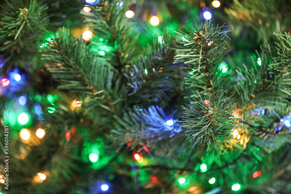 Christmas tree with bright string lights, closeup. Bokeh effect