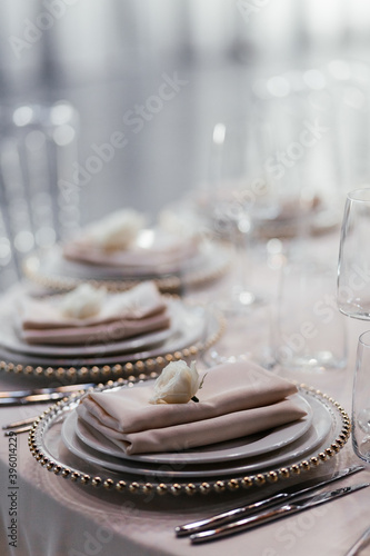 Set of plates on the wedding banquet. Luxury table set in the restaurant. Glasses and plates. Decorations. Beige background. Wedding banquet. 