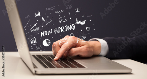 Businessman working on laptop with NOW HIRING inscription, modern business concept