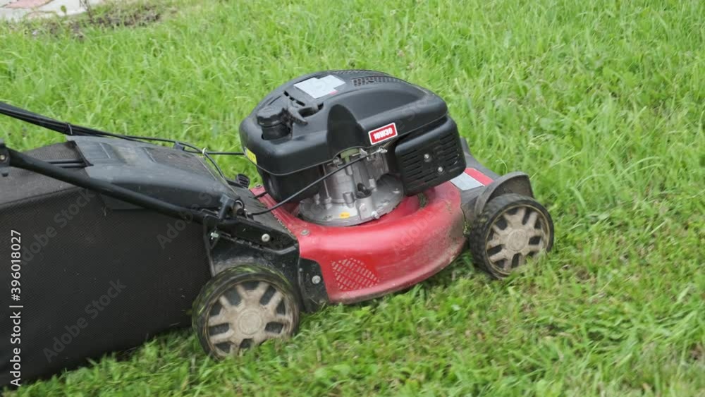 Gardening service. Male gardener mowing lawn with motorized lawnmower in summer day. Pushing mower machine tool an overgrown backyard. Gardening service. Male gardener mowing lawn with motorized lawnmower in summer day. Pushing mower machine tool an overgrown backyard.