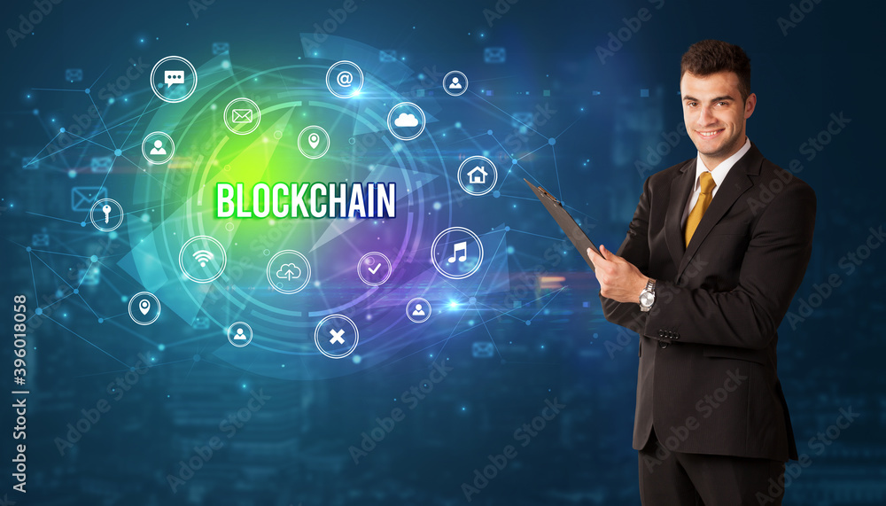 Businessman thinking in front of technology related icons and BLOCKCHAIN inscription, modern technology concept Businessman thinking in front of technology related icons and BLOCKCHAIN inscription, modern technology concept