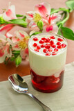 White yogurt with pomegranate jam on a background of flowers.
