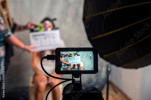 Foto Operator holding clapperboard during the production of short film inside a studio with young actress on stage