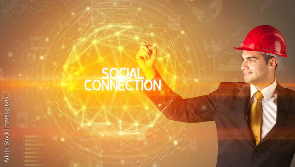 Handsome businessman with helmet drawing SOCIAL CONNECTION inscription, social construction concept Handsome businessman with helmet drawing SOCIAL CONNECTION inscription, social construction concept