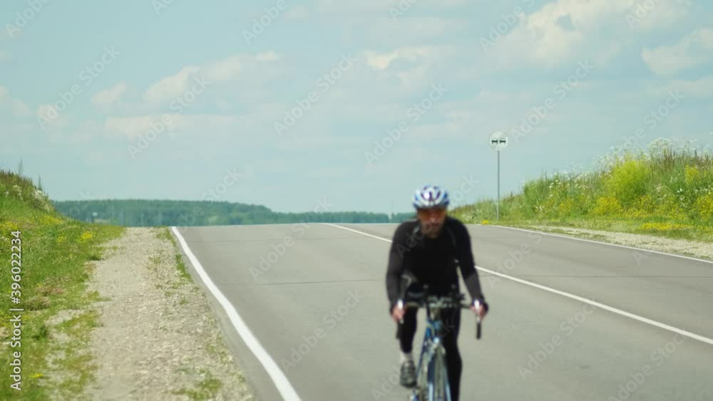 Professional cyclist rides on an empty highway, beautiful nature on the horizon on a Sunny day.