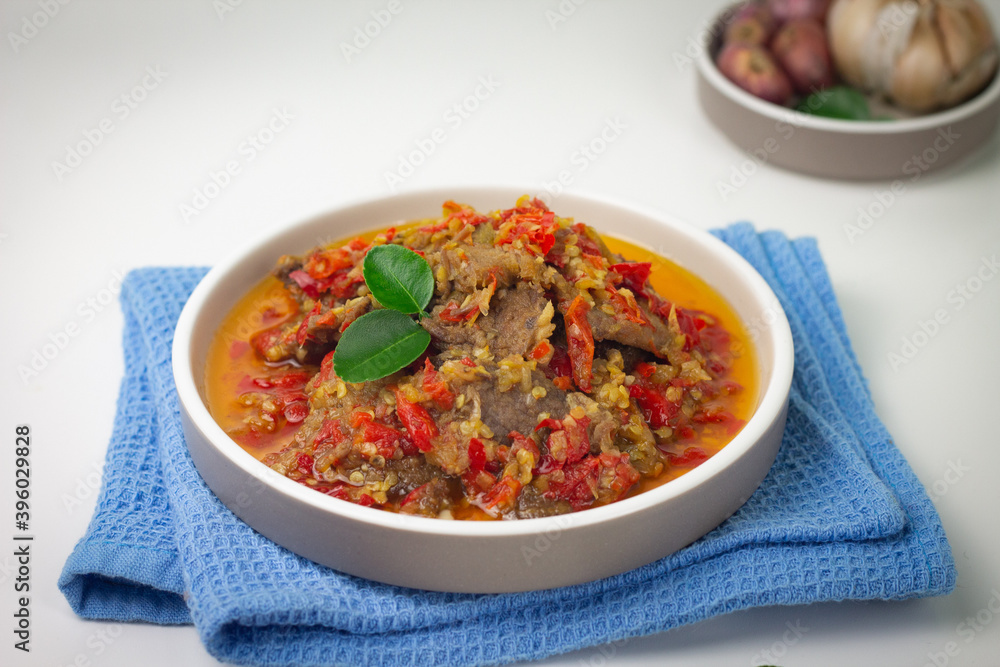 Dendeng Balado, Indonesian traditional beef cuisine from Padang, West Sumatra with slices beef cooked with some spices and a lot of chilies. Served on ceramic plate and isolated white background. Dendeng Balado, Indonesian traditional beef cuisine from Padang, West Sumatra with slices beef cooked with some spices and a lot of chilies. Served on ceramic plate and isolated white background.