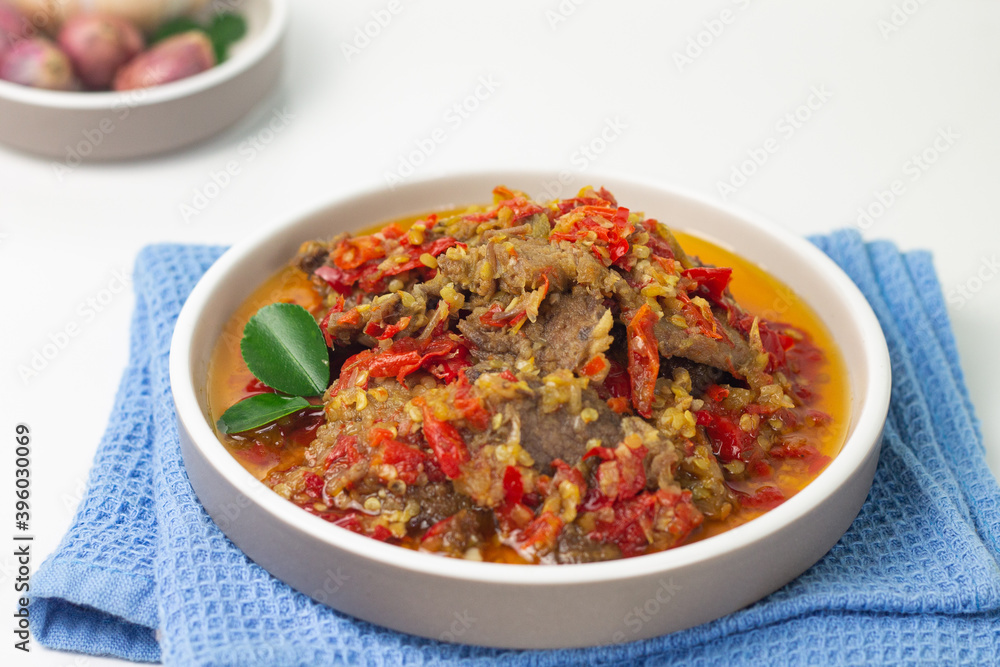 Dendeng Balado, Indonesian traditional beef cuisine from Padang, West Sumatra with slices beef cooked with some spices and a lot of chilies. Served on ceramic plate and isolated white background. Dendeng Balado, Indonesian traditional beef cuisine from Padang, West Sumatra with slices beef cooked with some spices and a lot of chilies. Served on ceramic plate and isolated white background.