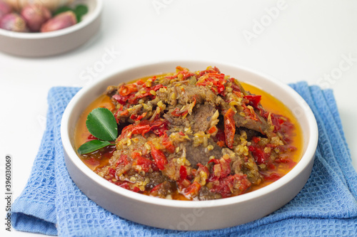 Dendeng Balado, Indonesian traditional beef cuisine from Padang, West Sumatra with slices beef cooked with some spices and a lot of chilies. Served on ceramic plate and isolated white background. 