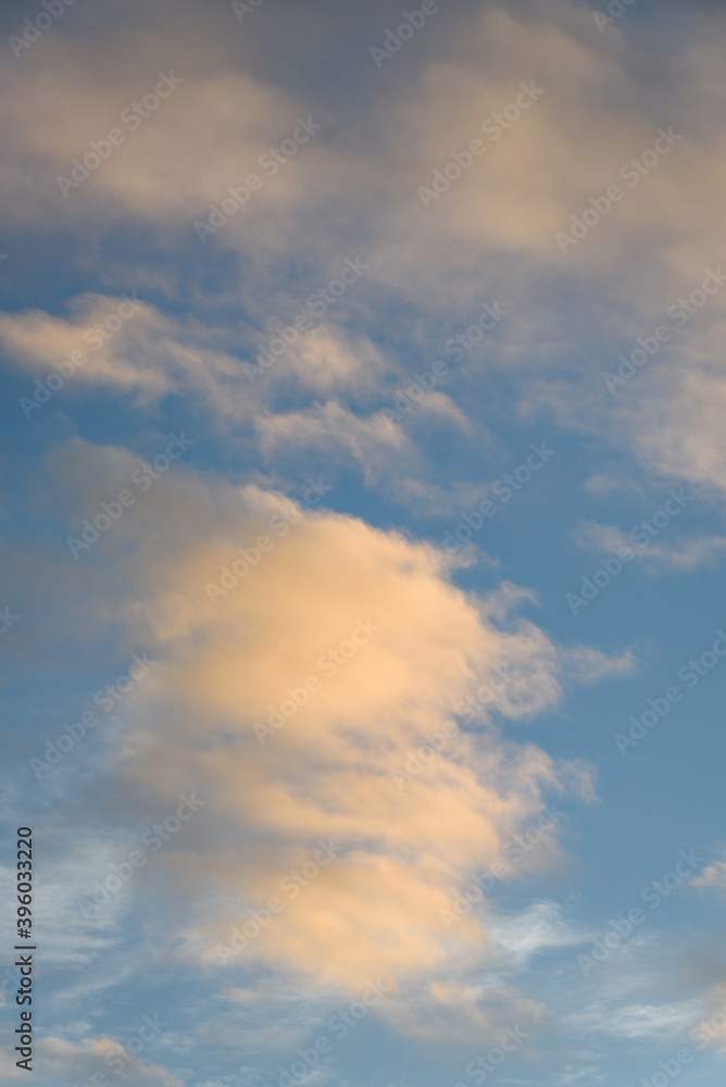 Peaceful evening light on white clouds and blue sky, as a nature background
