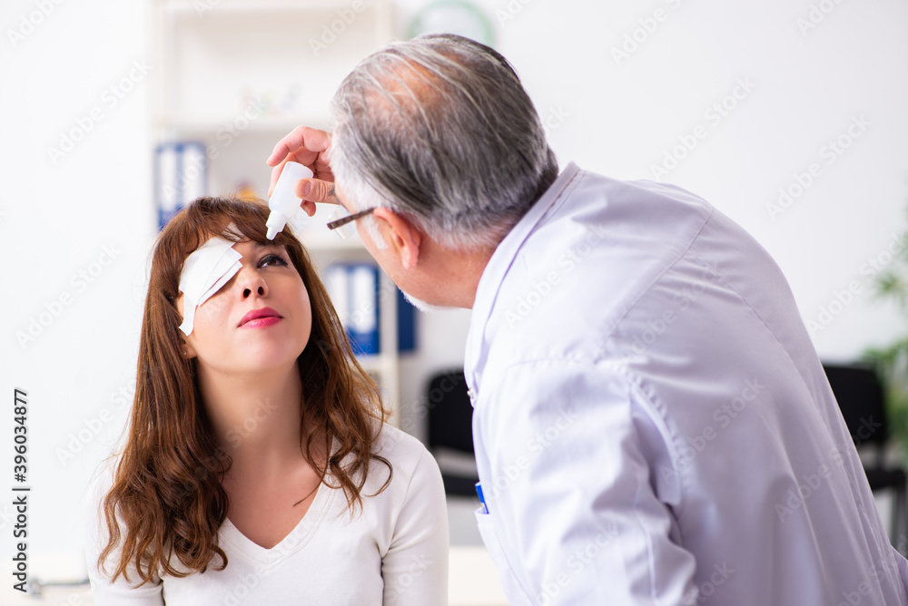 Young woman visiting old male doctor ophthalmologist Young woman visiting old male doctor ophthalmologist