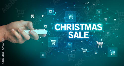 hand holding wireless peripheral with CHRISTMAS SALE inscription, online shopping concept