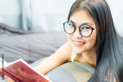 Beautiful asin student women lying on cozy bed reading book
