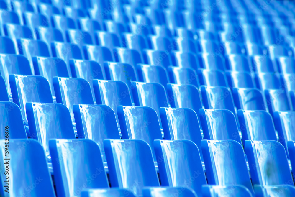 geometric photo of a set of blue seats on the outdoor grandstand of a sports court.