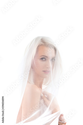 delicate airy beauty Portrait of a young blonde with light makeup under a transparent cloth. High exposure