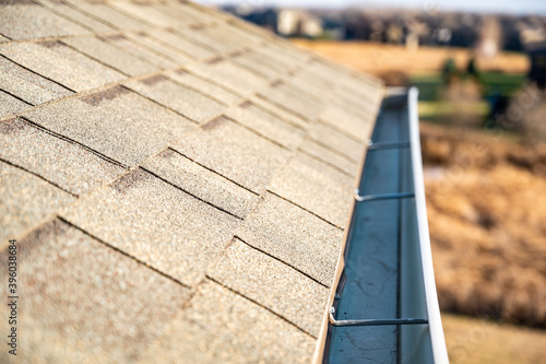 View from above looking down the edge of a roof gutter with clips and edge of shingles photo