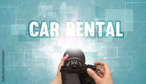 Close-up of a hand holding digital camera with CAR RENTAL inscription, traveling concept