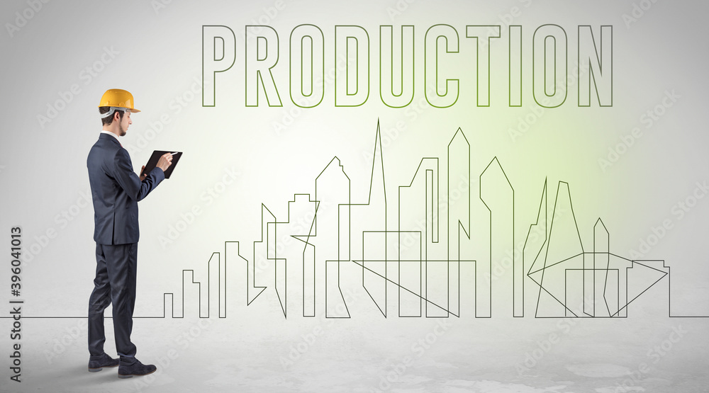 Businessman in hard hat holding blueprint with PRODUCTION inscription, engineering and architecture concept Businessman in hard hat holding blueprint with PRODUCTION inscription, engineering and architecture concept