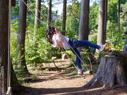 森の中のブランコで遊ぶ女の子