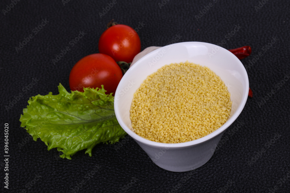 Raw couscous in the bowl served salad leaves, tomato and pepper Raw couscous in the bowl served salad leaves, tomato and pepper