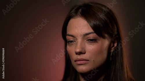 charming woman is crying, closeup of face in studio, sadness and sorrow, tears on cheek
