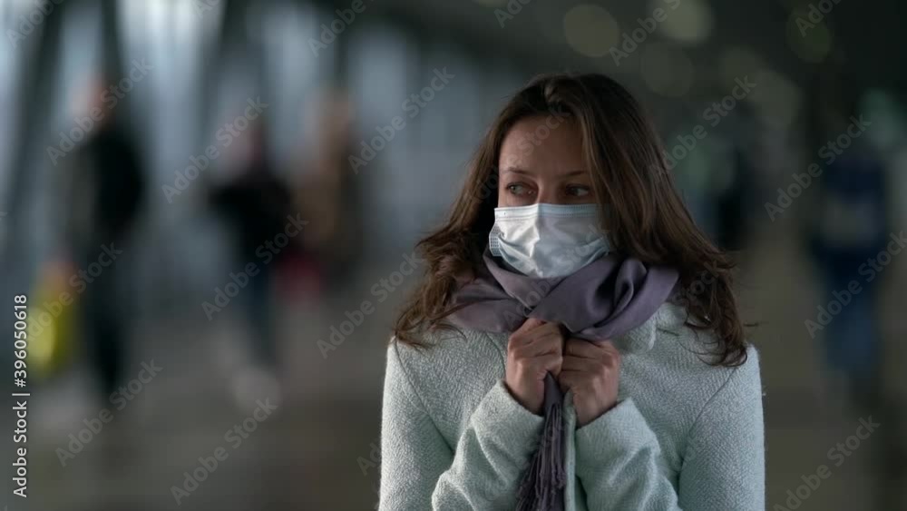 woman with face mask is standing in pedestrian tunnel of subway or mall and wrapping in coat woman with face mask is standing in pedestrian tunnel of subway or mall and wrapping in coat